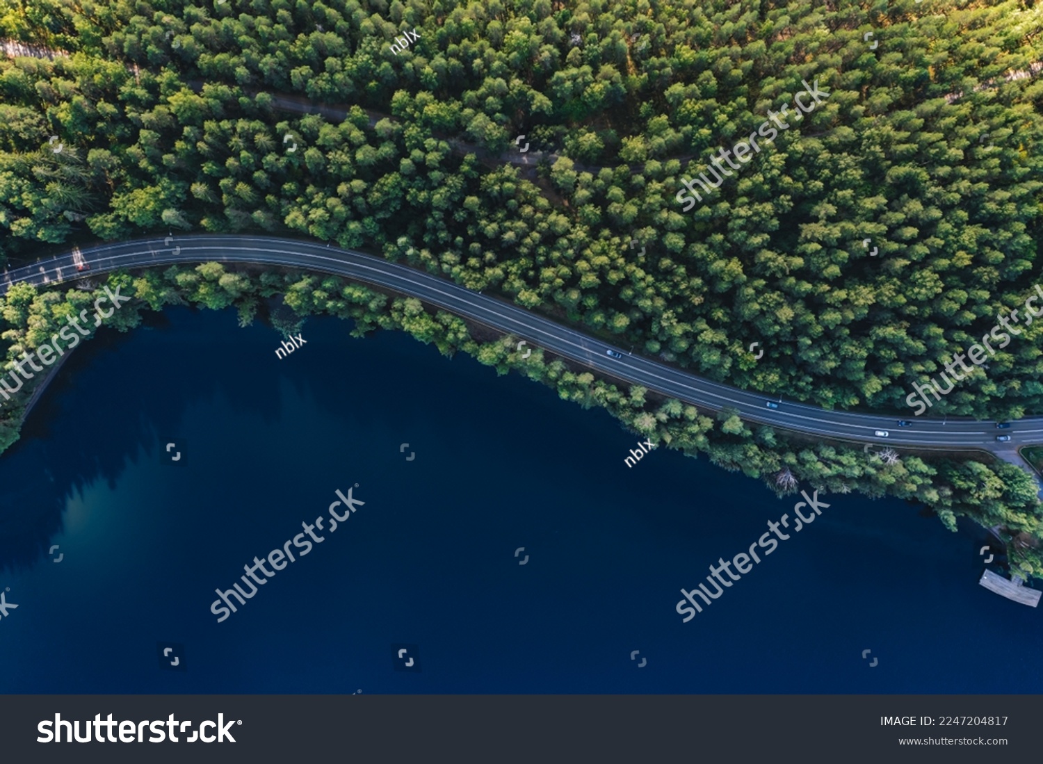 Aerial view of road with green woods by blue lakes water in summer Finland. Stock-foto