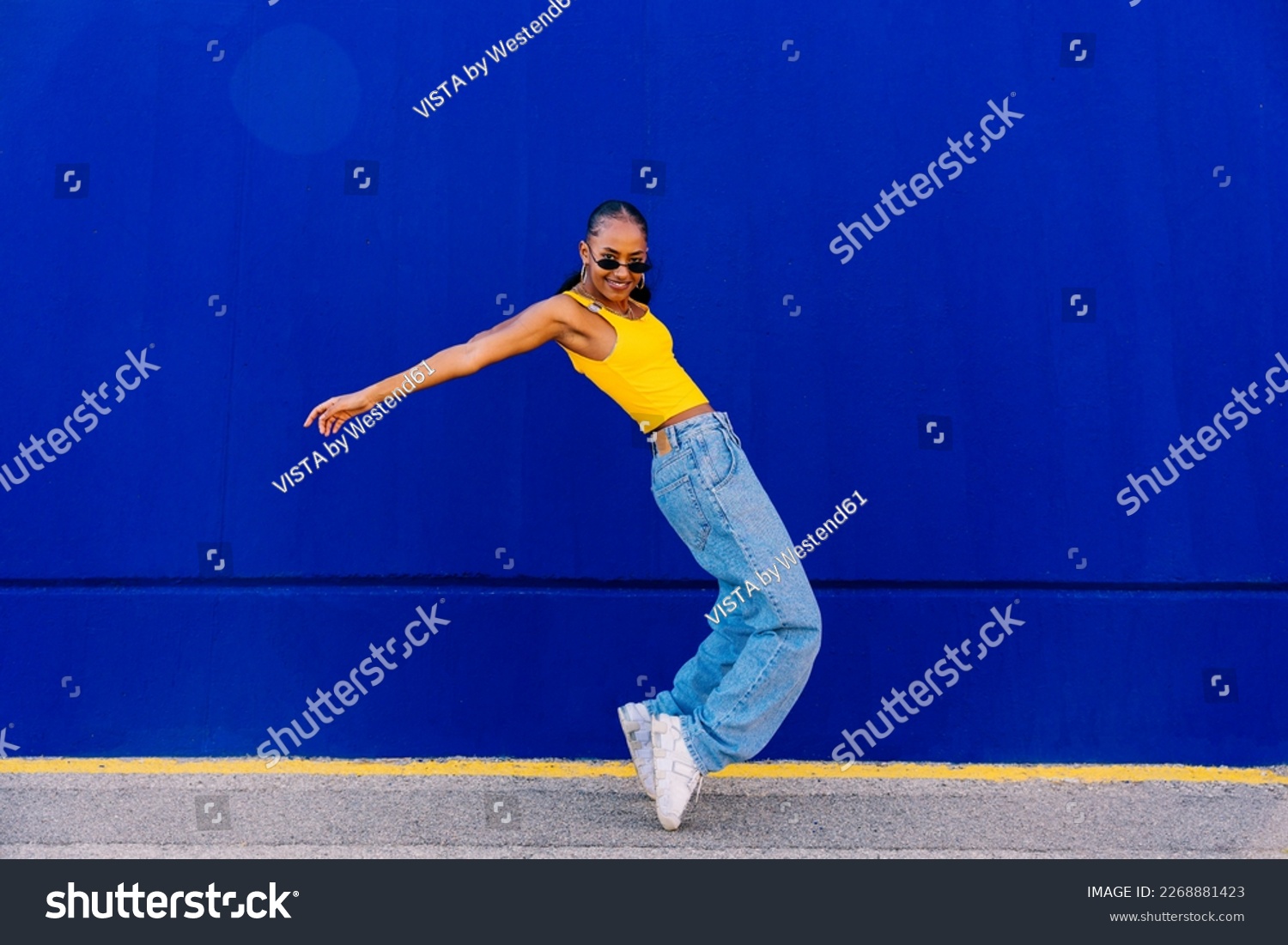 Dancer on tiptoes dancing by blue wall on footpath Stock-foto