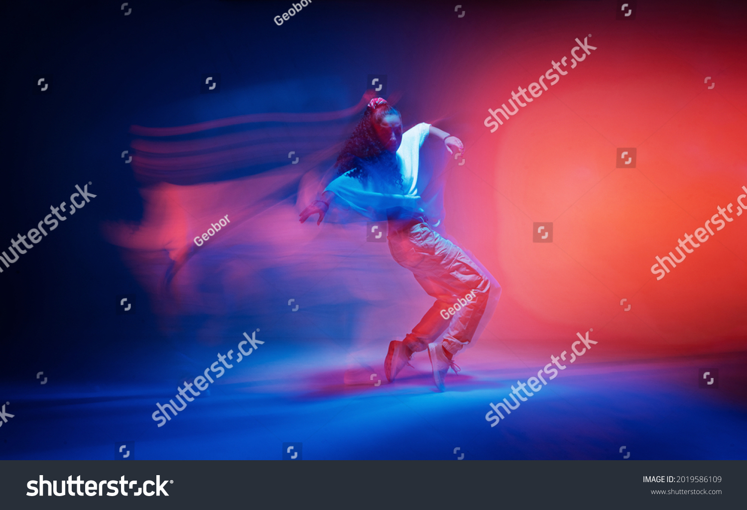 Dancing female standing on tiptoe in colourful neon studio light. Long exposure. Contemporary hip hop dance Stock-foto