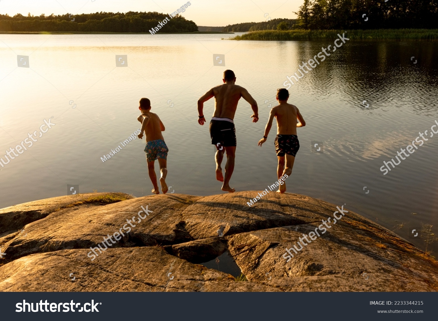 Father and sons running towards lake during vacation Stock-foto