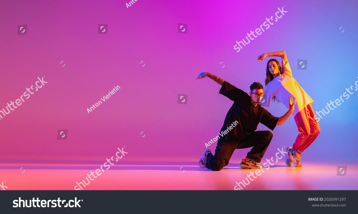 Flyer. Strange body movements. Two young people, guy and girl dancing contemporary dance over pink background in neon light. Modern dance aesthetics concept Stock-foto