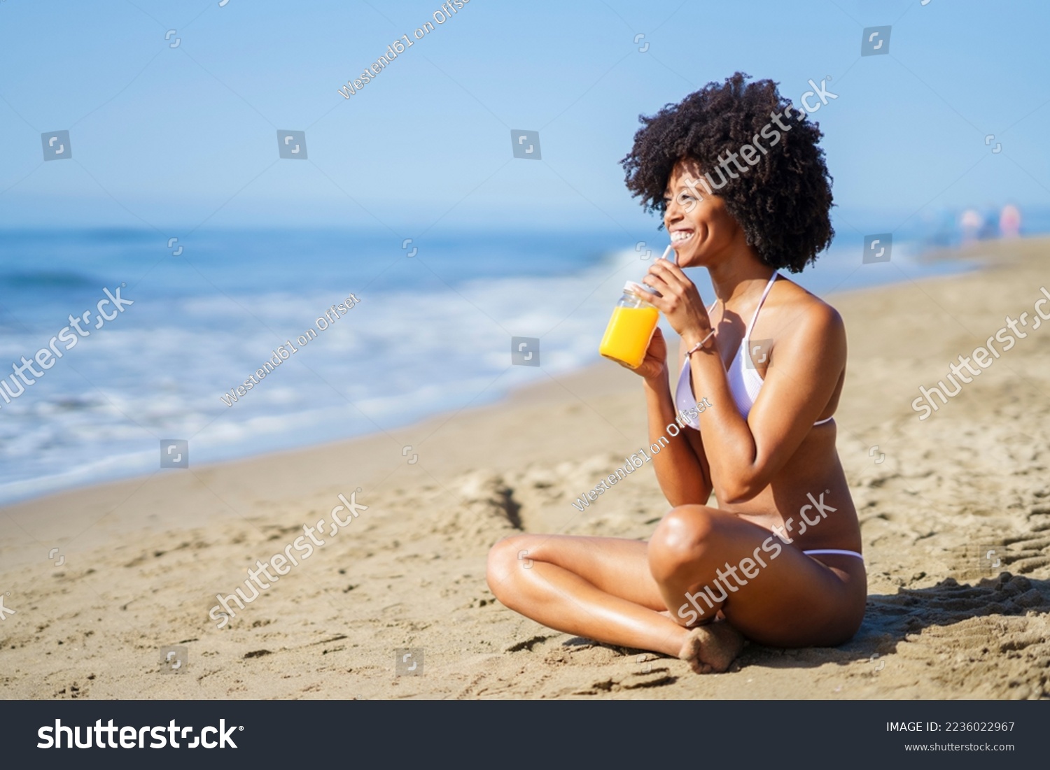 Happy woman drinking orange juice at beach in summer Stock-foto