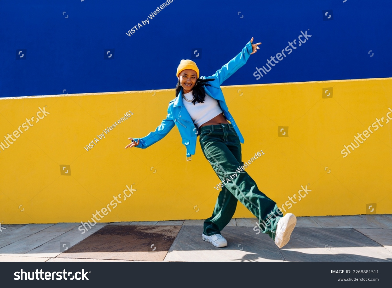 Smiling young dancer dancing with arms outstretched on footpath Stock-foto