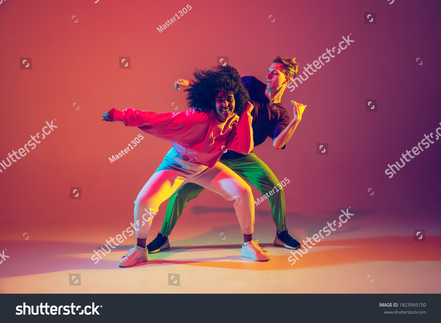 Stilfuld mand og kvinde danser hip-hop i lyst tøj på grøn baggrund på dansehallen i neonlys. Ungdomskultur, hip-hop, bevægelse, stil og mode, handling. Fashionable portræt. Stock-foto