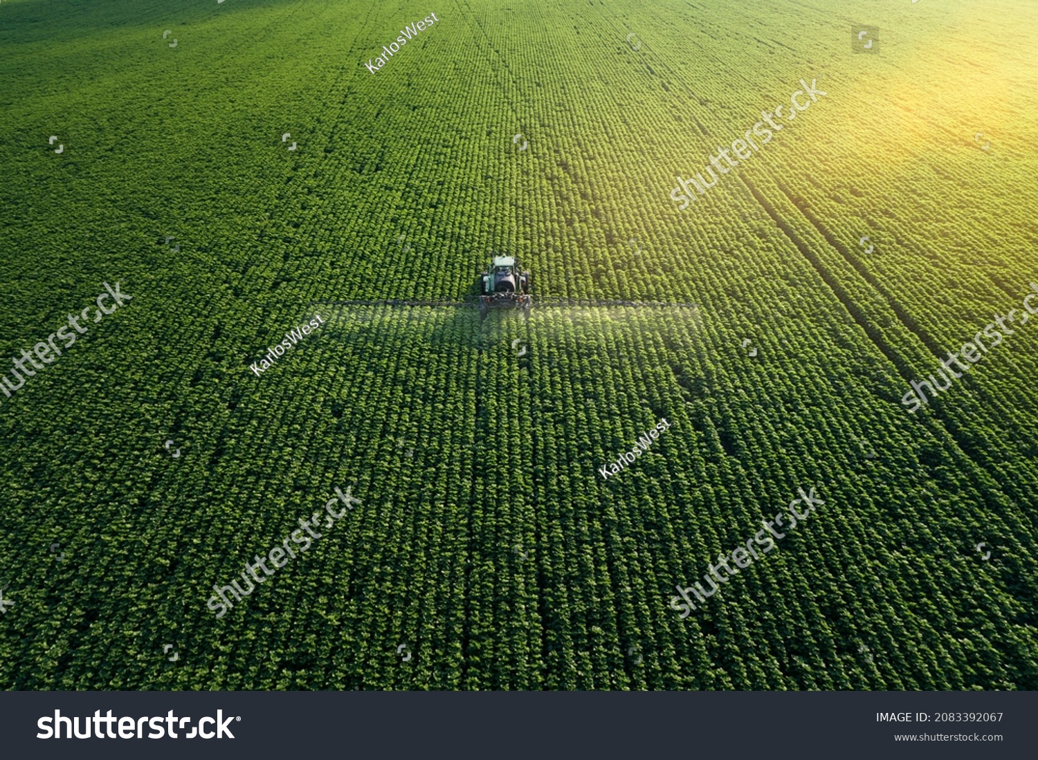 Taking care of the Crop. Aerial view of a Tractor fertilizing a cultivated agricultural field. Stock-foto